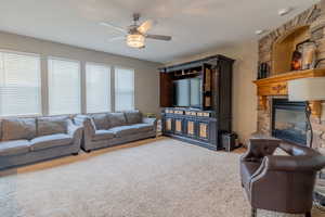 Living room featuring light carpet, ceiling fan, and a fireplace