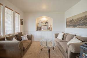 Carpeted living room with wainscoting and a decorative wall