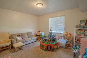Game room with light colored carpet and a textured ceiling
