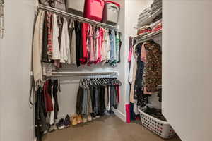 Primary bedroom walk in closet with light colored carpet