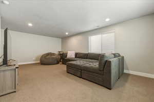Living area with light carpet and recessed lighting