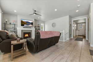 Living room with a ceiling fan, a fireplace, and recessed lighting