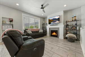 Living area with a tiled fireplace, ceiling fan, wood tiled floors, and recessed lighting