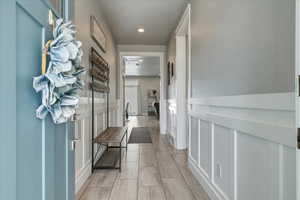 Corridor with a decorative wall, recessed lighting, and wainscoting