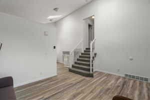 Stairs with wood finished floors, a skylight, and a high ceiling