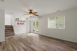 Unfurnished living room with a ceiling fan and dark wood-style flooring
