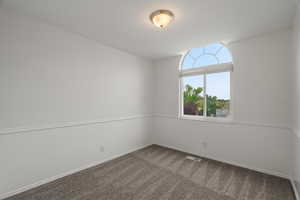 Spare room featuring dark carpet and baseboards