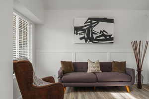 Sitting room featuring wood finished floors, a decorative wall, and wainscoting