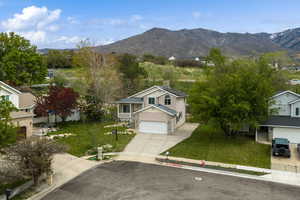 View of front of property with concrete driveway, a mountain view, a front lawn, and an attached garage