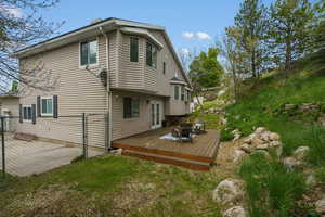 Rear view of house featuring a wooden deck, a gate, and a lawn