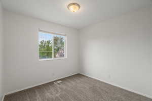 Empty room featuring dark carpet and baseboards