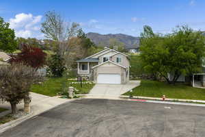 View of front facade featuring a front lawn, driveway, a mountain view, and an attached garage