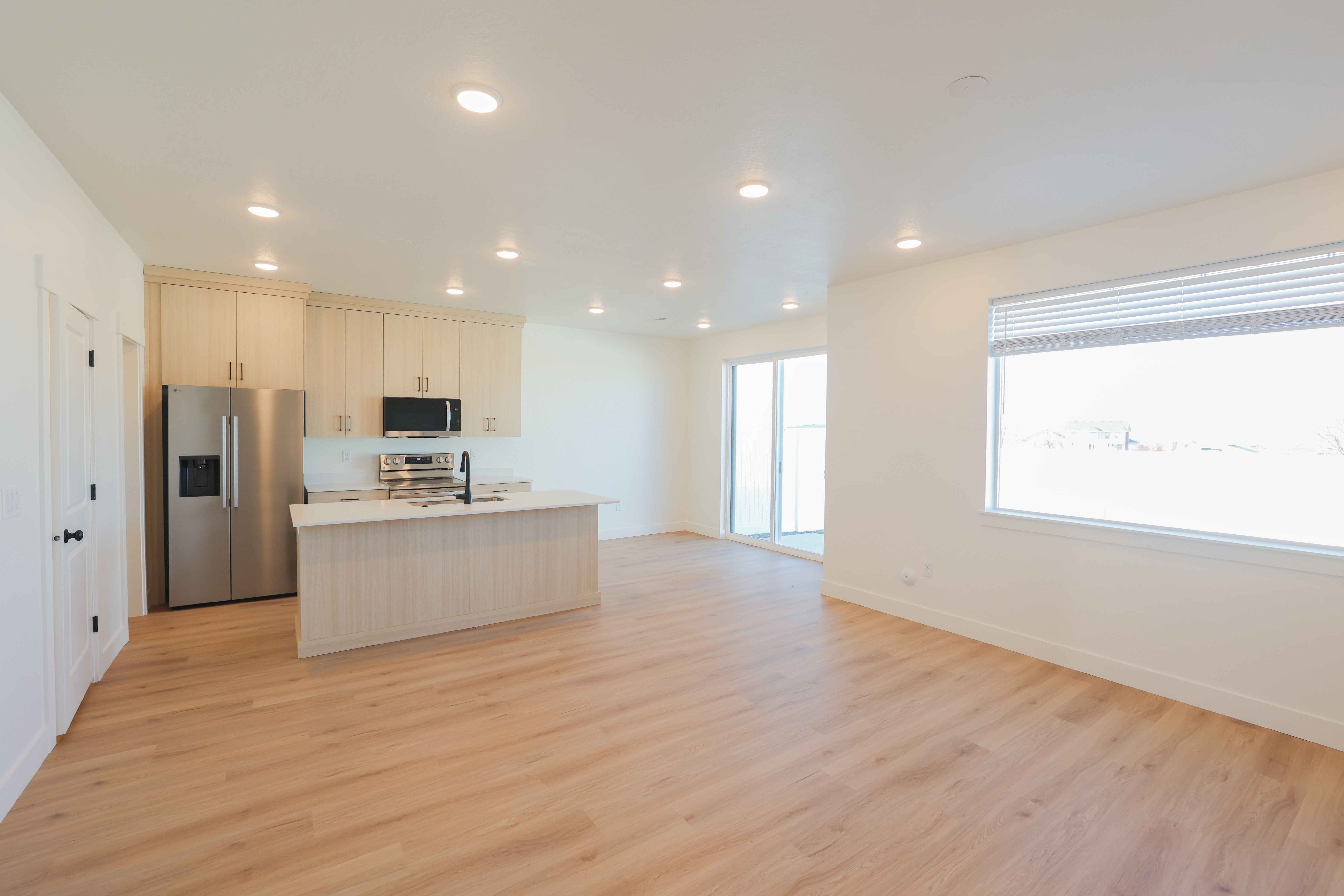 Kitchen featuring stainless steel appliances, a kitchen island with sink, recessed lighting, light countertops, and light wood-type flooring