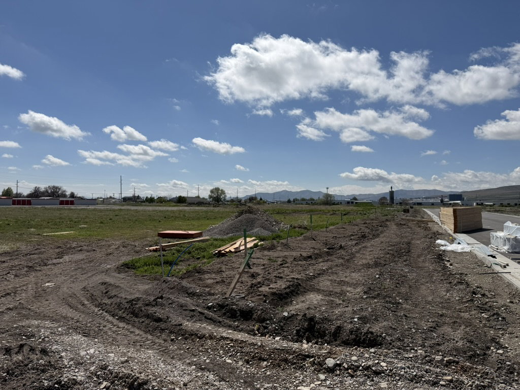 Cleared building lot with excavated earth, gravel, and visible utility lines