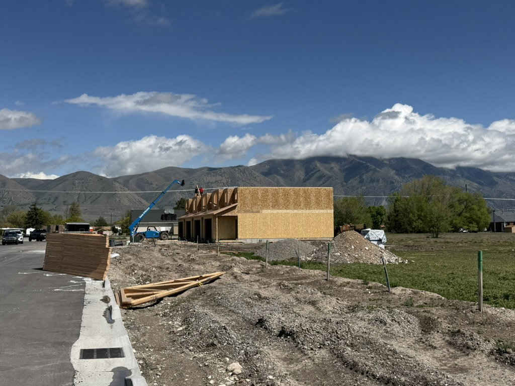 New construction framing in progress with structural wood sheathing and roof trusses visible