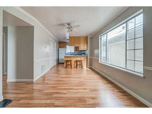 Kitchen with crown molding, a breakfast bar area, ceiling fan, light wood finished floors, and a peninsula