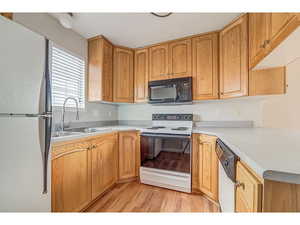 Kitchen featuring white appliances, light countertops, and light wood finished floors