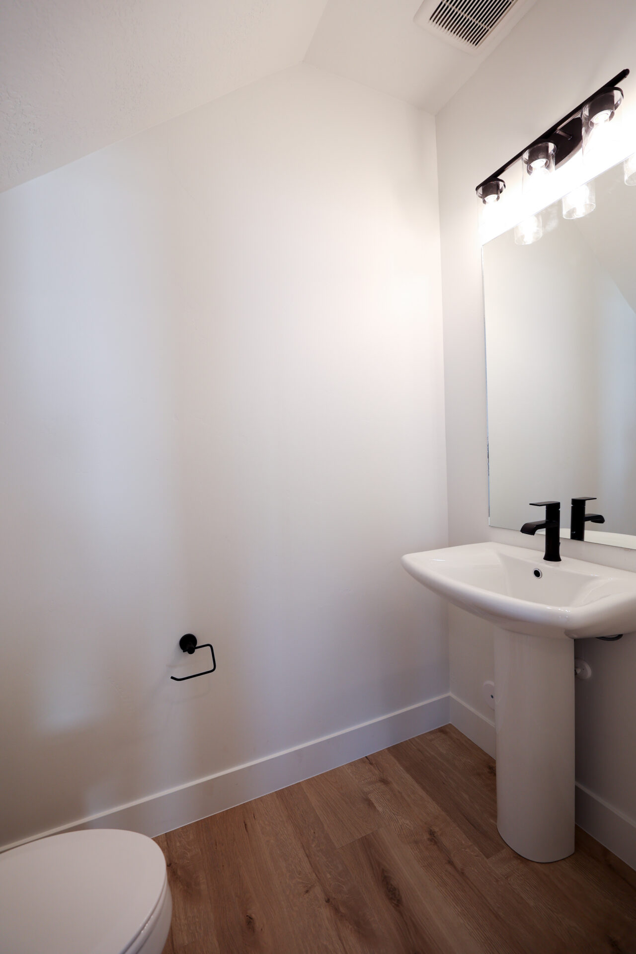 Half bath with dark wood-style floors and vaulted ceiling