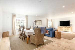 Dining area featuring light wood finished floors, a textured ceiling, and recessed lighting