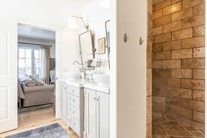 Bathroom with double vanity, light wood finished floors, ensuite bathroom, and a shower