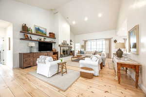 Living area featuring lofted ceiling, a fireplace with raised hearth, light wood-style flooring, and recessed lighting