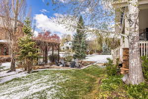 Yard layered in snow featuring a fire pit, a lawn, and a patio