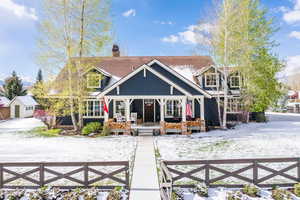 View of front of home featuring covered porch, a fenced front yard, and a chimney