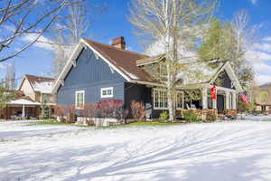 View of side of home featuring a chimney and covered porch