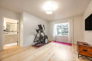 Workout room featuring light wood-style floors and a textured ceiling