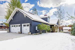 View of side of home featuring a garage, board and batten siding, a chimney, and driveway