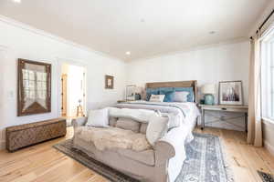 Bedroom featuring multiple windows, light wood-type flooring, and ornamental molding