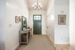 Entrance foyer featuring suspended lighting, lofted ceiling, and light wood finished floors