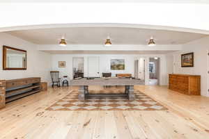 Playroom with arched walkways, light wood finished floors, and billiards
