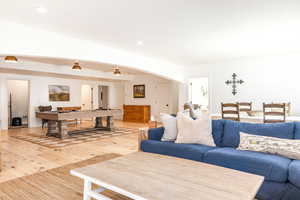 Living area with light wood-style flooring, arched walkways, pool table, and recessed lighting