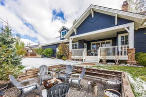 Back of property with a fire pit, a porch, and a chimney