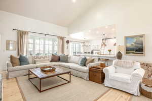 Living area with hanging lights, lofted ceiling, and light wood finished floors