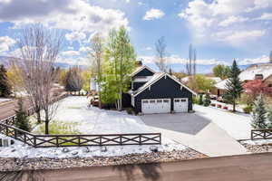 View of front of home with an attached garage, a chimney, a mountain view, driveway, and a fenced front yard