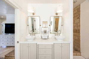 Full bath featuring double vanity, tiled shower, and a textured ceiling