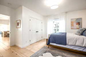 Bedroom featuring a closet, light wood-style flooring, and a textured ceiling