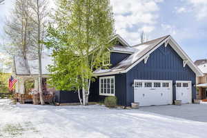 View of front facade featuring board and batten siding, roof with shingles, and an attached garage