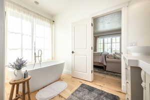 Bathroom with light wood finished floors, a soaking tub, ensuite bathroom, and vanity