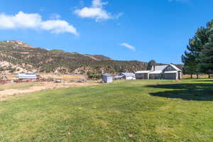 View of grassy yard featuring a mountain view, a view of countryside, and an outbuilding