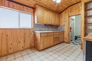 Kitchen featuring wood walls, light floors, light countertops, decorative backsplash, and a vaulted wooden ceiling