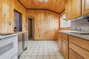 Kitchen featuring light flooring, white range oven, tasteful backsplash, light countertops, and wood walls