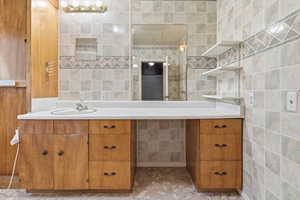 Full bathroom with vanity and tile walls