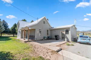 View of side of home featuring a metal roof, covered porch, and a lawn