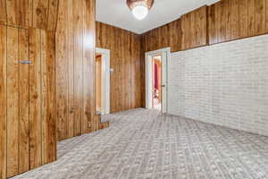 Carpeted empty room featuring wood walls and a textured ceiling