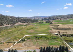 Aerial view of sparsely populated area featuring property parcel outlined and a mountainous background