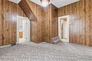Additional living space featuring light colored carpet, wooden walls, and a textured ceiling