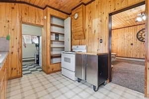 Kitchen featuring wooden walls, light floors, white range with electric cooktop, crown molding, and wooden ceiling
